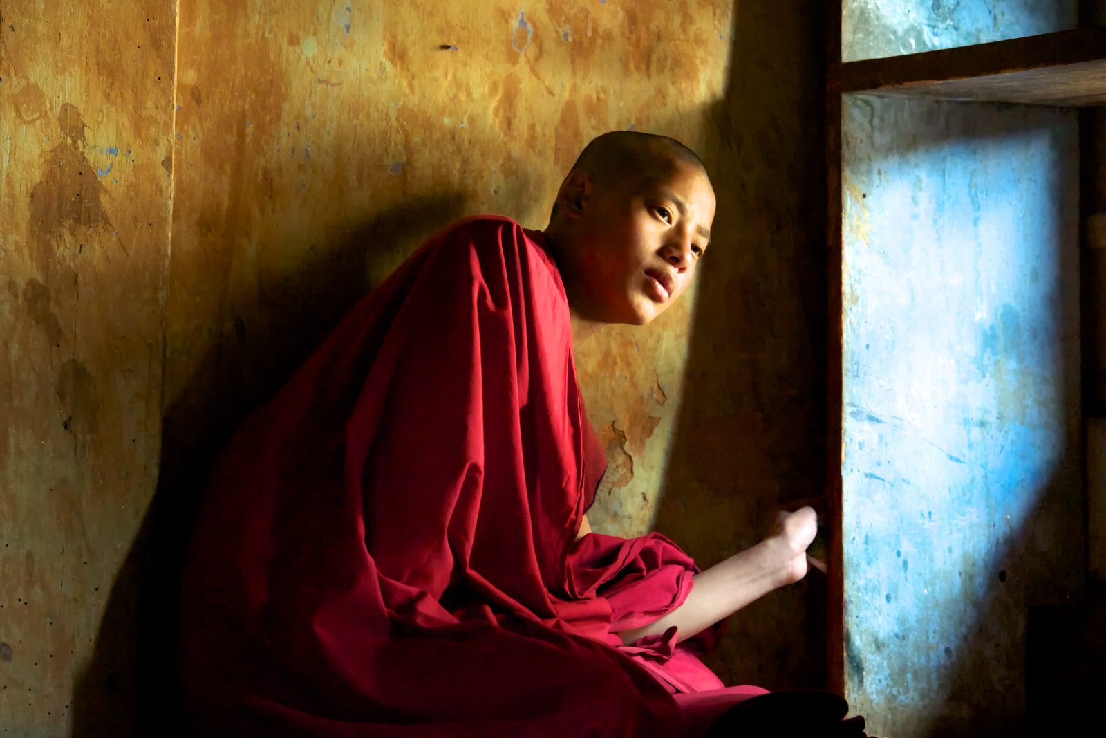 Buddhist monk contemplating by a window in warm light