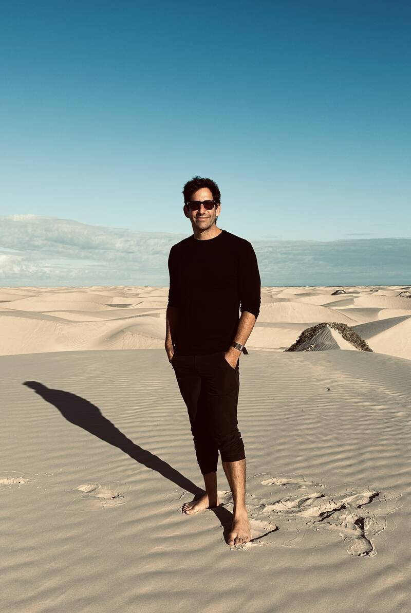Samuel Strauch standing barefoot on sand dunes